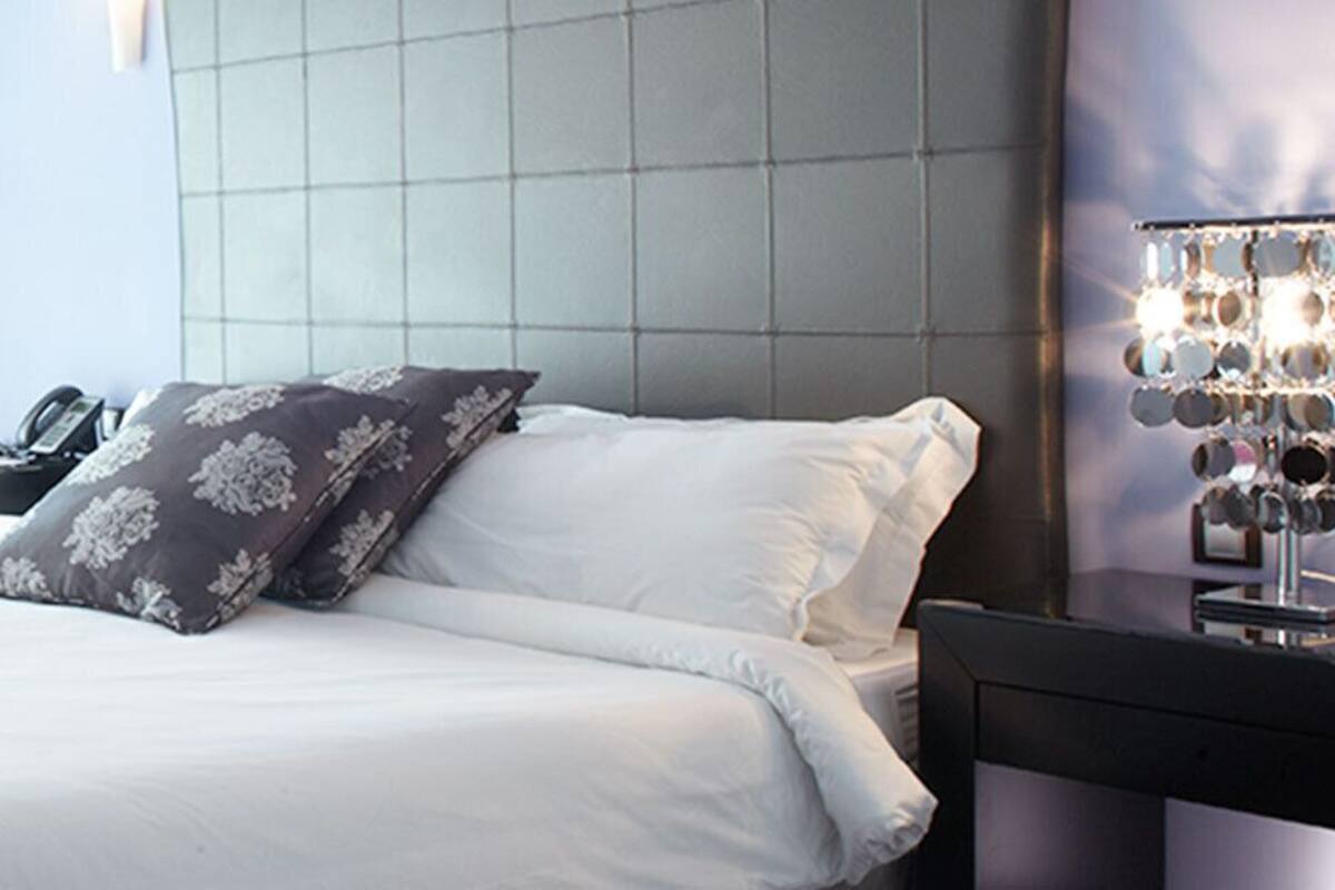 Une chambre d’hôtel avec un grand lit, une table de chevet, une chaise, un bureau et une lampe.
