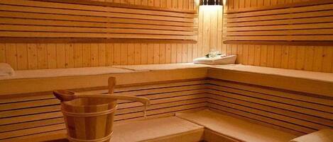 A sauna with wooden benches and a wooden bucket.