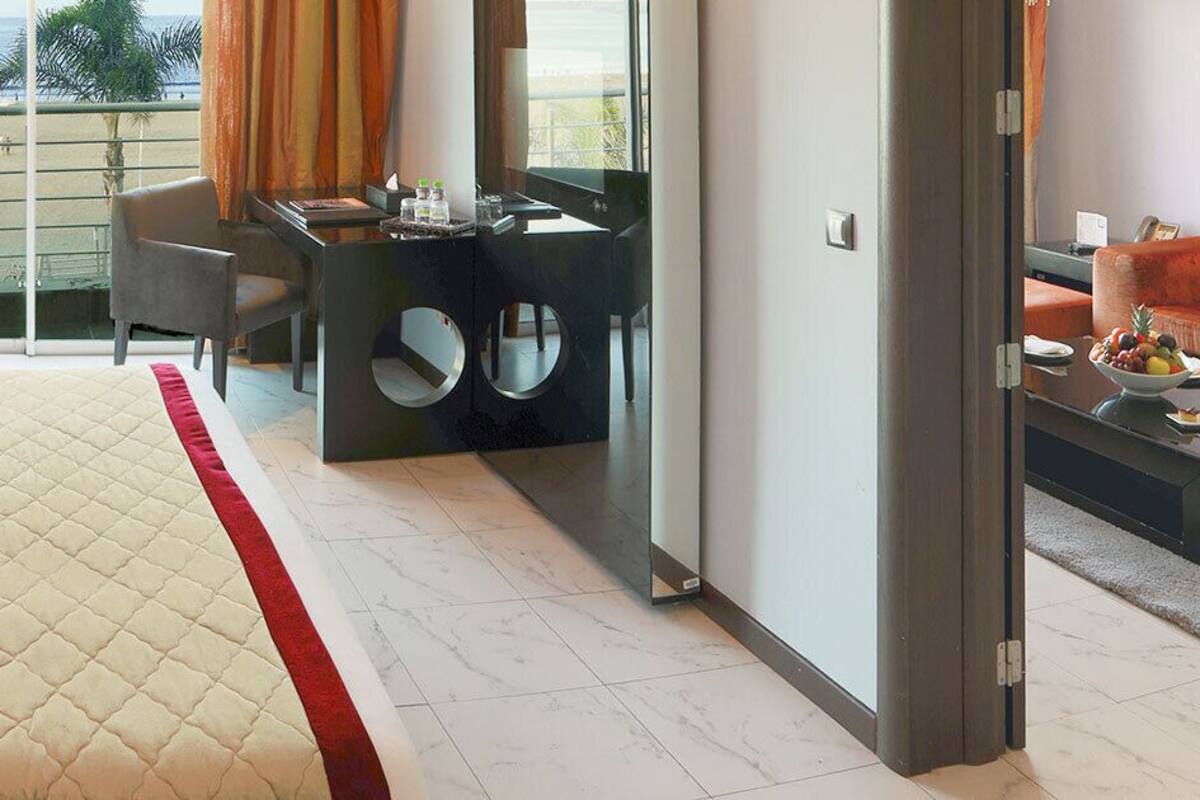 Une chambre d’hôtel avec un grand lit, un bureau et une vue sur la mer.