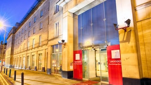 A hotel entrance with a prominent red and blue sign, large glass doors, and a well-lit facade. - Leonardo Hotel Edinburgh Haymarket (Edinburgh)