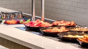 A buffet with various food items including meats, vegetables, and a fruit bowl. - Leonardo Hotel Edinburgh Haymarket (Edinburgh)