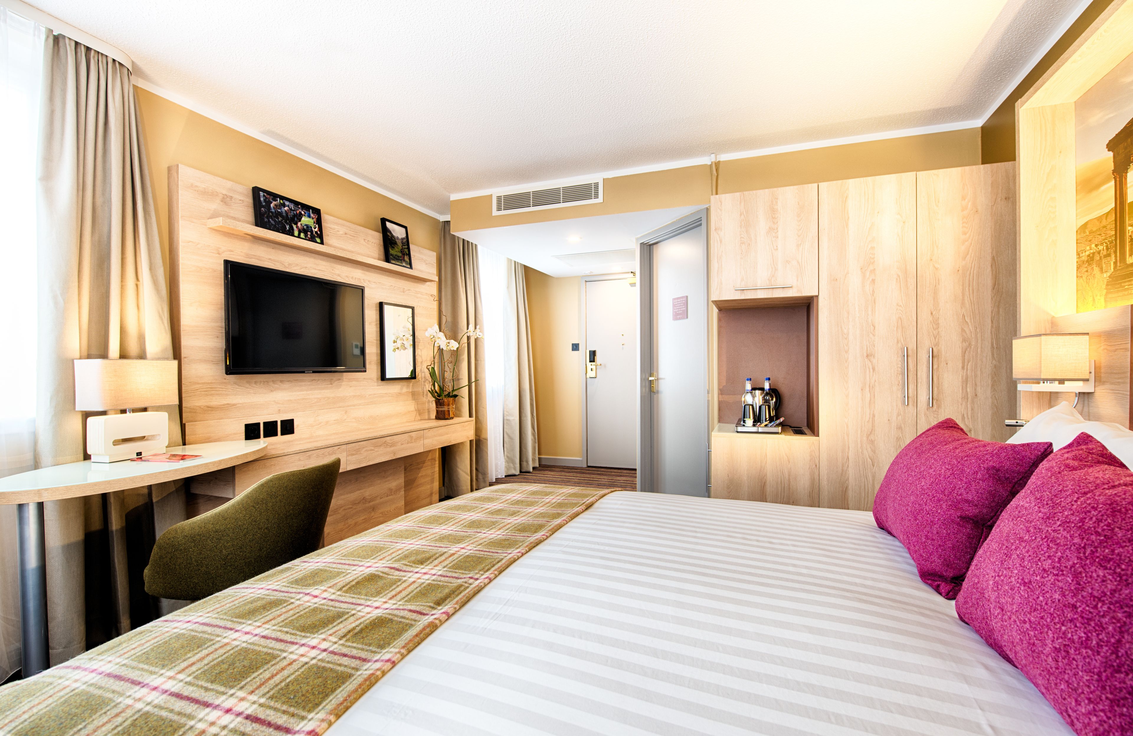 Une chambre d’hôtel équipée d’un lit, d’un bureau, d’une télévision et d’un mini-bar.