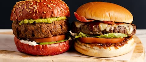 Two burgers on a wooden board.