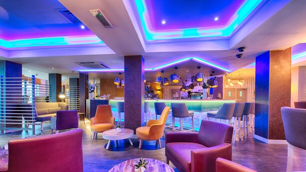 A modern lounge area with multiple seating options, a bar in the background, and ambient lighting. - Leonardo Hotel Edinburgh Haymarket (Edinburgh)