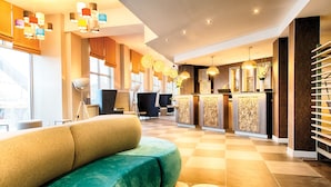 A modern hotel lobby with a checkered floor, a reception desk, and a green sofa. - Leonardo Hotel Edinburgh Haymarket (Edinburgh)