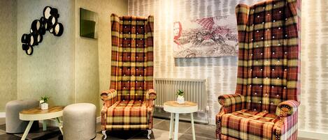A room with two plaid armchairs, a small round table, and a cushioned bench.