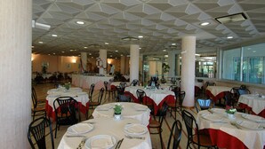 Un espace repas avec des tables rondes, des chaises et un plafond au design géométrique.