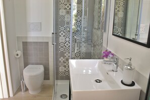 Habitación triple estándar, patio, planta baja | Baño | Regadera, amenidades de baño gratuitas, secadora de cabello, bidet 