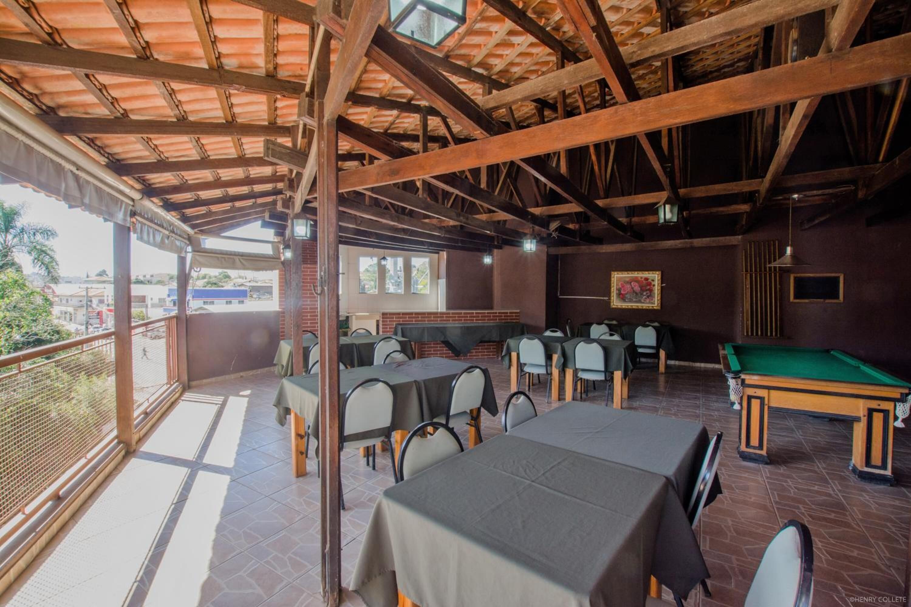 An outdoor dining area with tables and chairs, a pool table, and a view of the surrounding area.