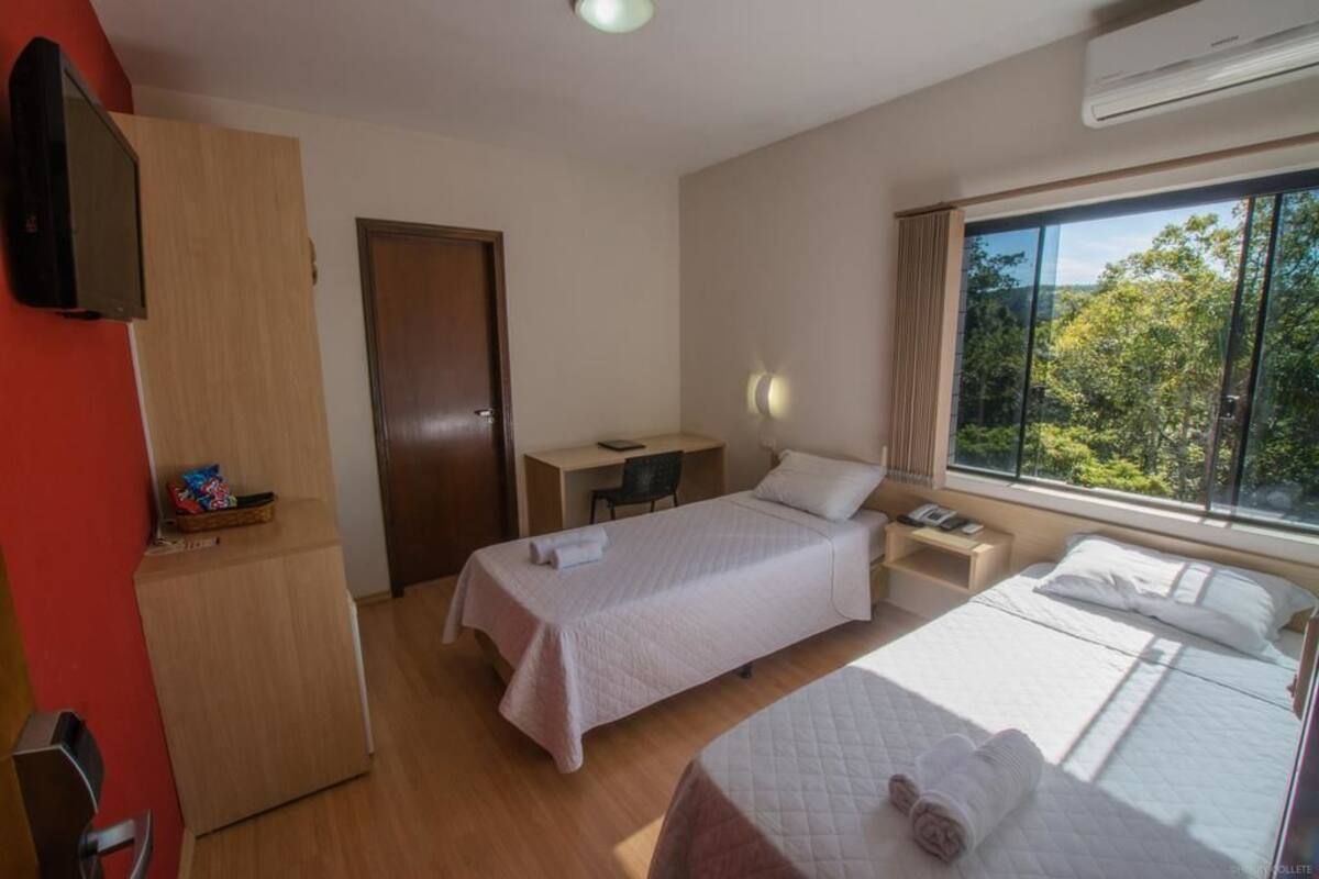 Une chambre d’hôtel équipée d’un lit, d’un bureau, d’une chaise et d’un téléviseur fixé au mur.
