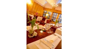 Comedor con mesas dispuestas para una comida, incluyendo platos, cubiertos y vasos.