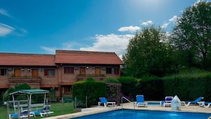 A swimming pool with lounge chairs, a covered seating area, and a building with a brick facade. - Villa De Merlo Hotel Spa (Merlo)
