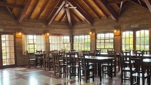 A spacious hall with wooden beams, large windows, and multiple tables and chairs. - Villa De Merlo Hotel Spa (Merlo)