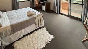 A bedroom with a bed, a desk, a TV, and a view of the outdoors. - Villa De Merlo Hotel Spa (Merlo)