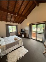 Un dormitorio con cama, escritorio, televisor y vistas al exterior.