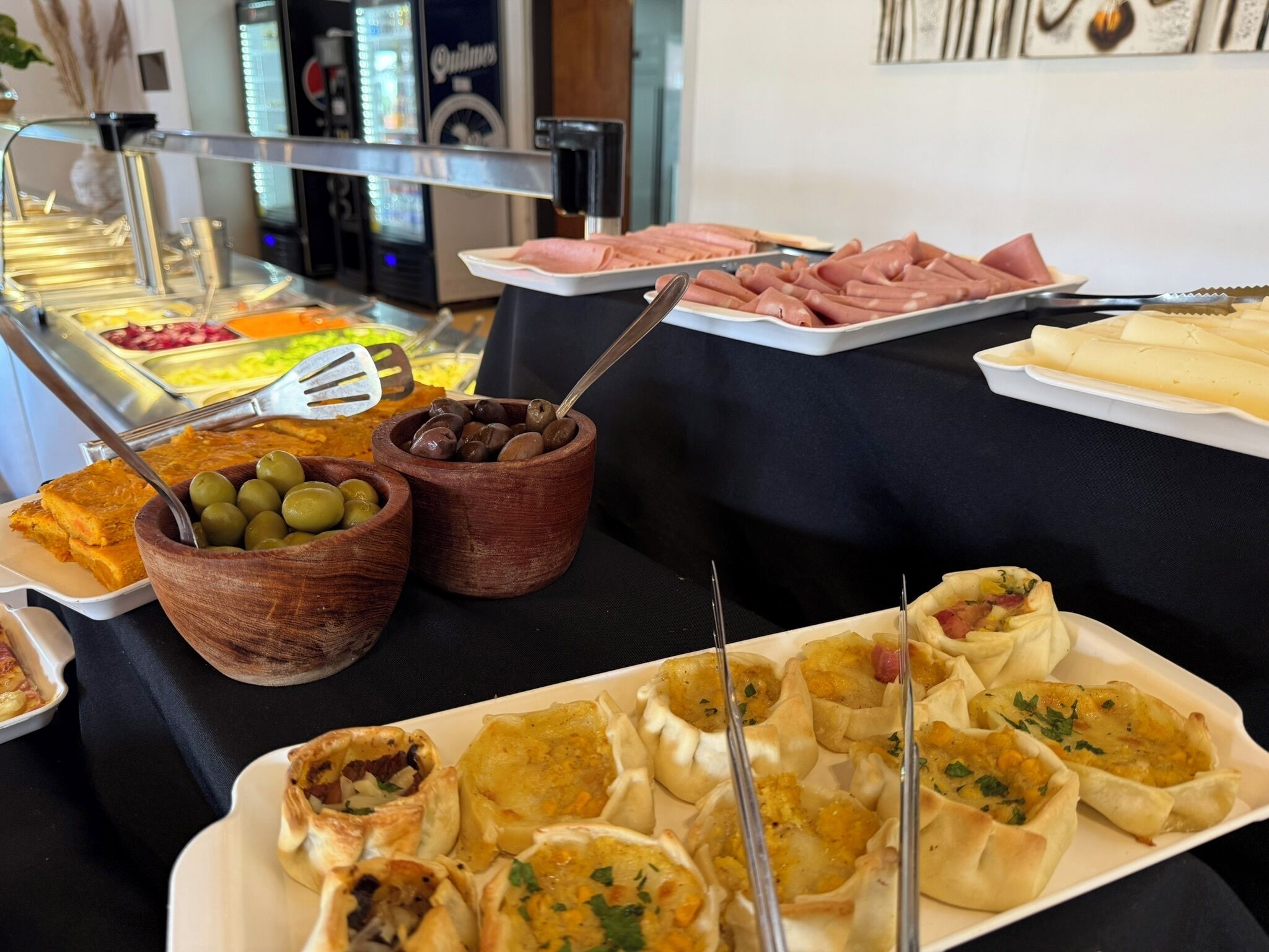 Un buffet proposant une variété de plats, notamment des olives, du chocolat et de la viande.