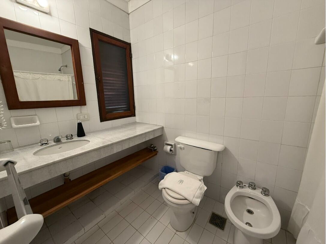 Un baño con inodoro, lavabo, bidé y espejo.