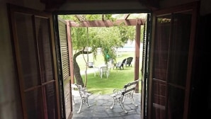 An open doorway leading to a patio with a stone floor, two benches, and a tree. - Villa De Merlo Hotel Spa (Merlo)