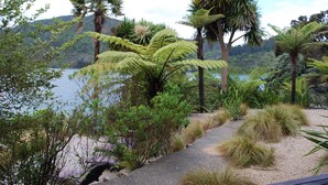 A pathway surrounded by lush greenery and palm trees, leading towards a body of water with hills in the background. - Lochmara Lodge (Lochmara Bay)