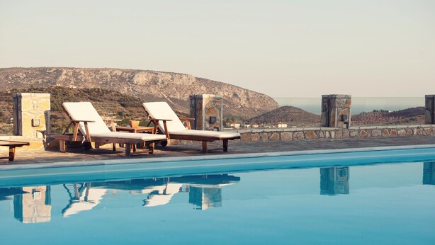 A poolside area with lounge chairs and a view of a mountainous landscape. - Perivoli Country Hotel & Retreat (Nafplio)