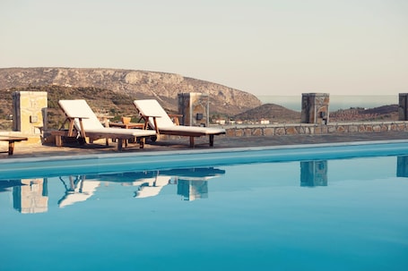 A poolside area with lounge chairs and a view of a mountainous landscape.