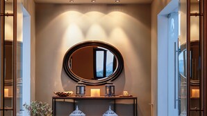 A modern hallway with a large mirror, a potted plant, and two lit lanterns on a console table. - Perivoli Country Hotel & Retreat (Nafplio)