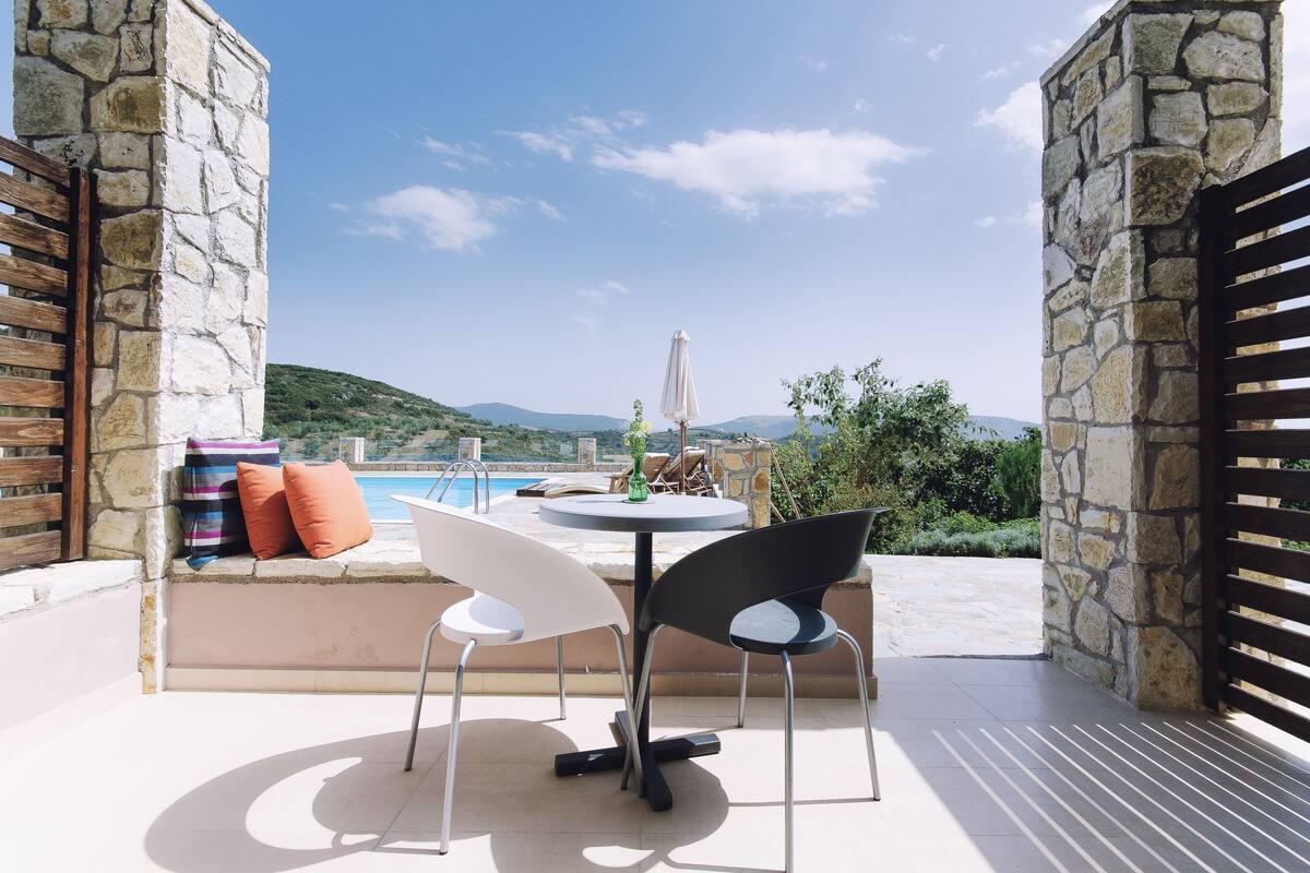 An outdoor seating area with a stone wall, a pool, and a view of the hills.