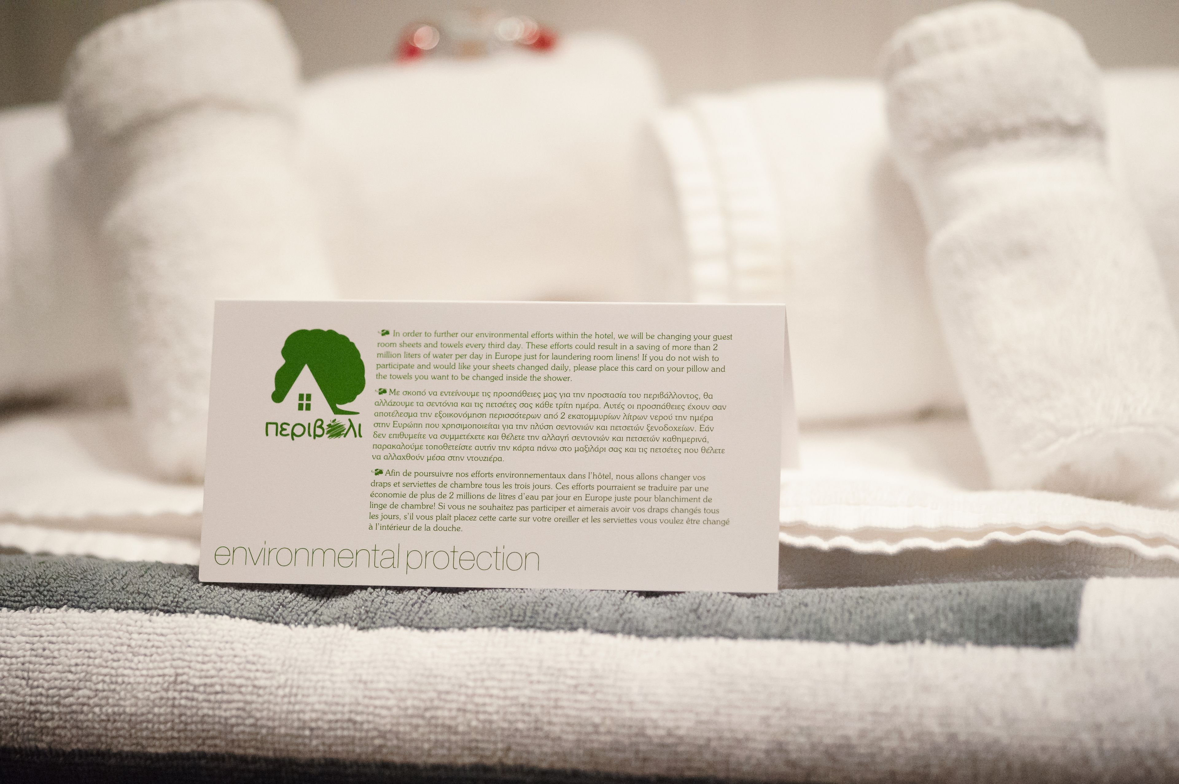 A card on a bed detailing environmental protection efforts, including towel reuse and linen changes.