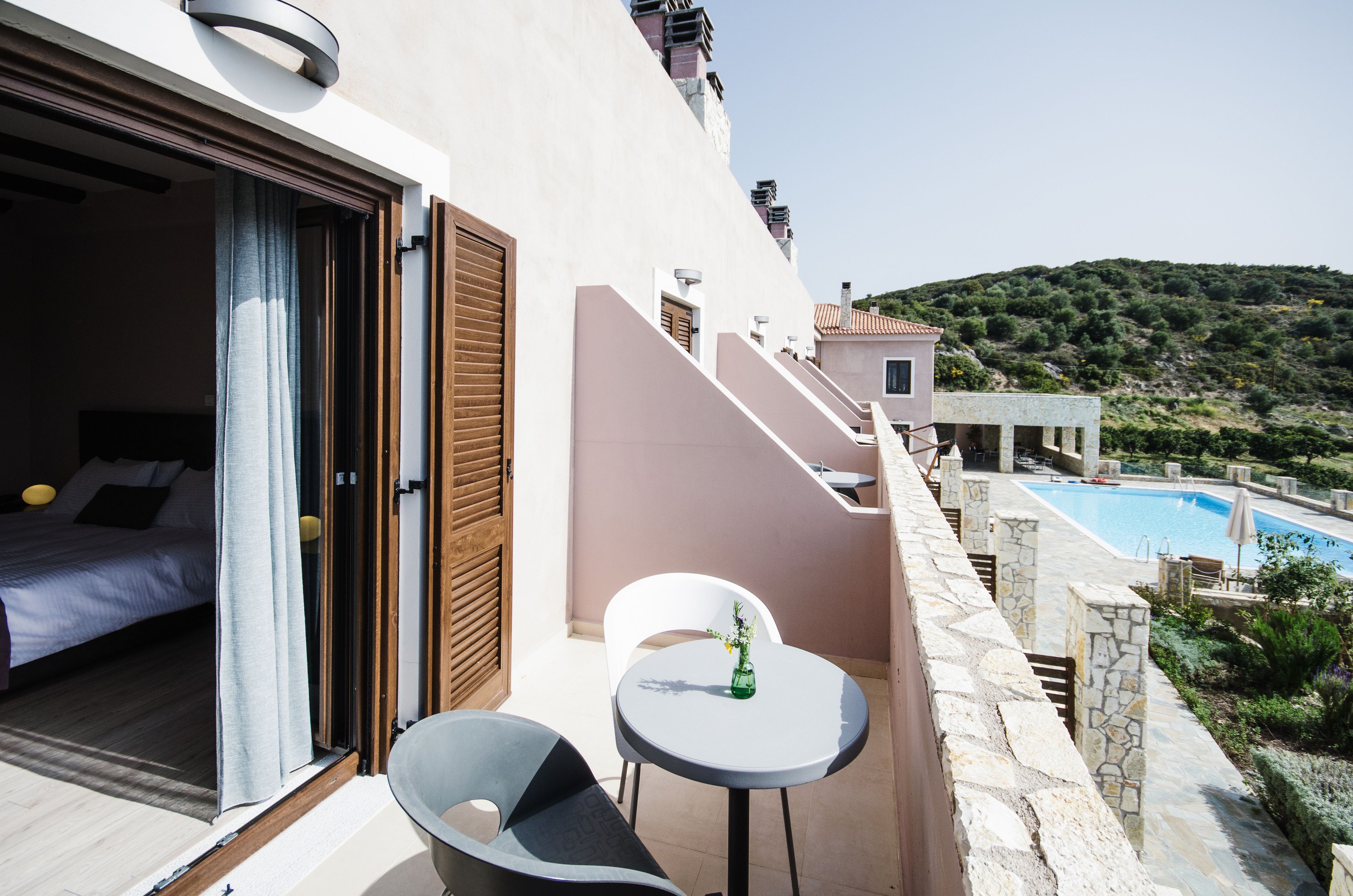 A balcony with a bed, a table with a vase, and a pool.