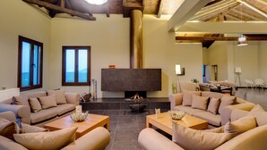A spacious living room with a fireplace, sofas, and a large TV. - Perivoli Country Hotel & Retreat (Nafplio)