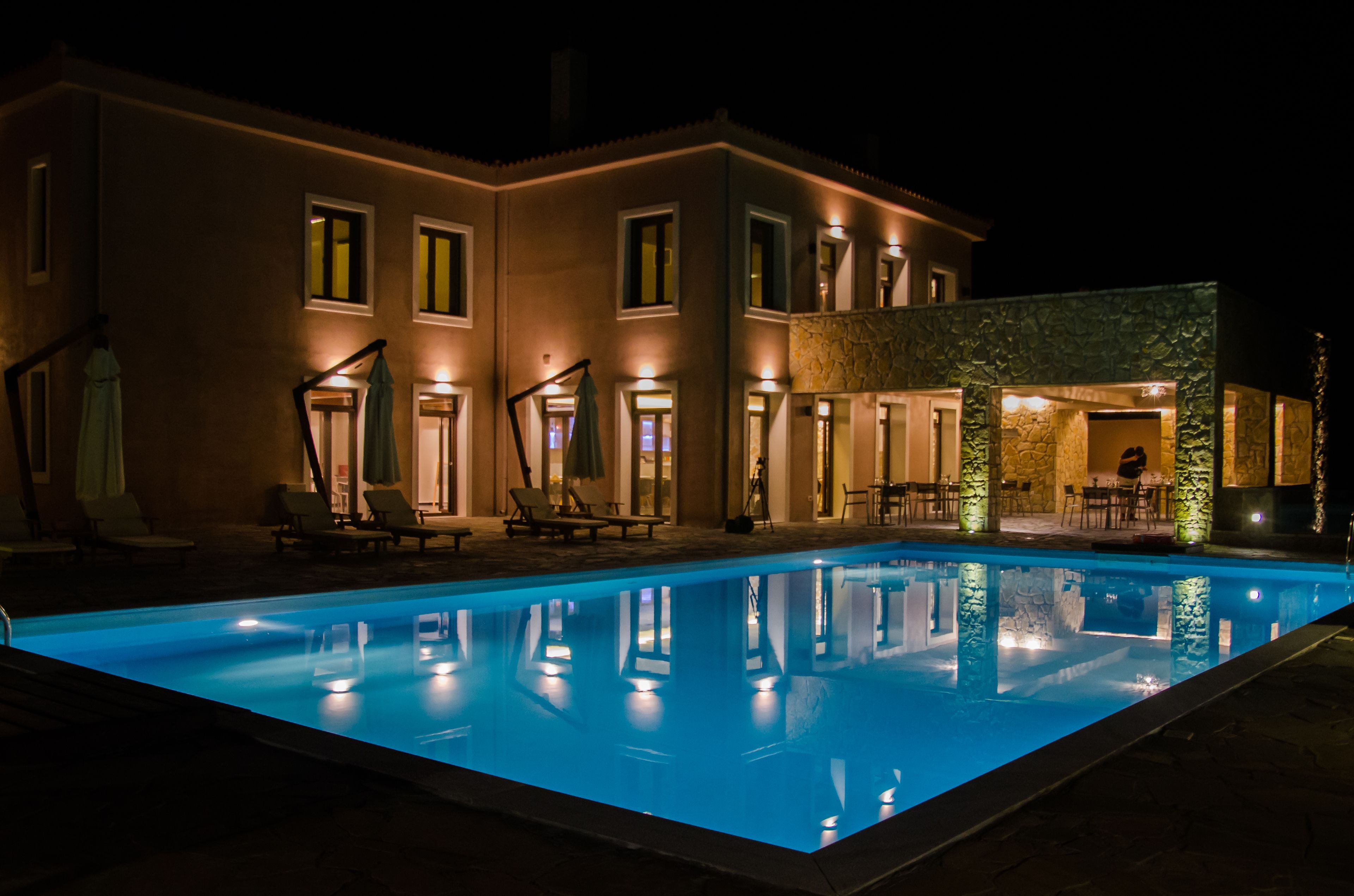 Una casa moderna con piscina, mobiliario exterior y fachada de piedra.