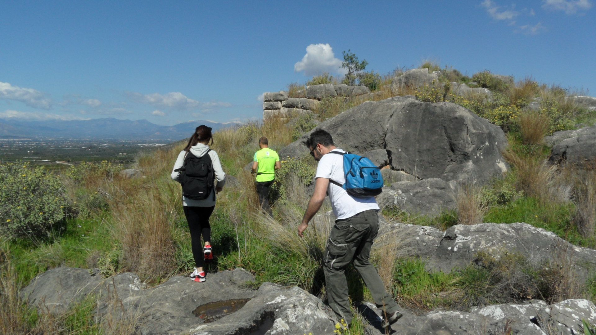Un grupo de excursionistas en un sendero pedregoso con vistas a montañas distantes.