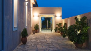 A modern building with a stone-paved entrance, potted plants, and illuminated entryway. - Perivoli Country Hotel & Retreat (Nafplio)