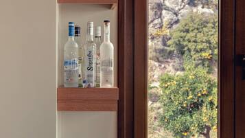 A wooden shelf with various liquor bottles and a bowl of fruit on a countertop.