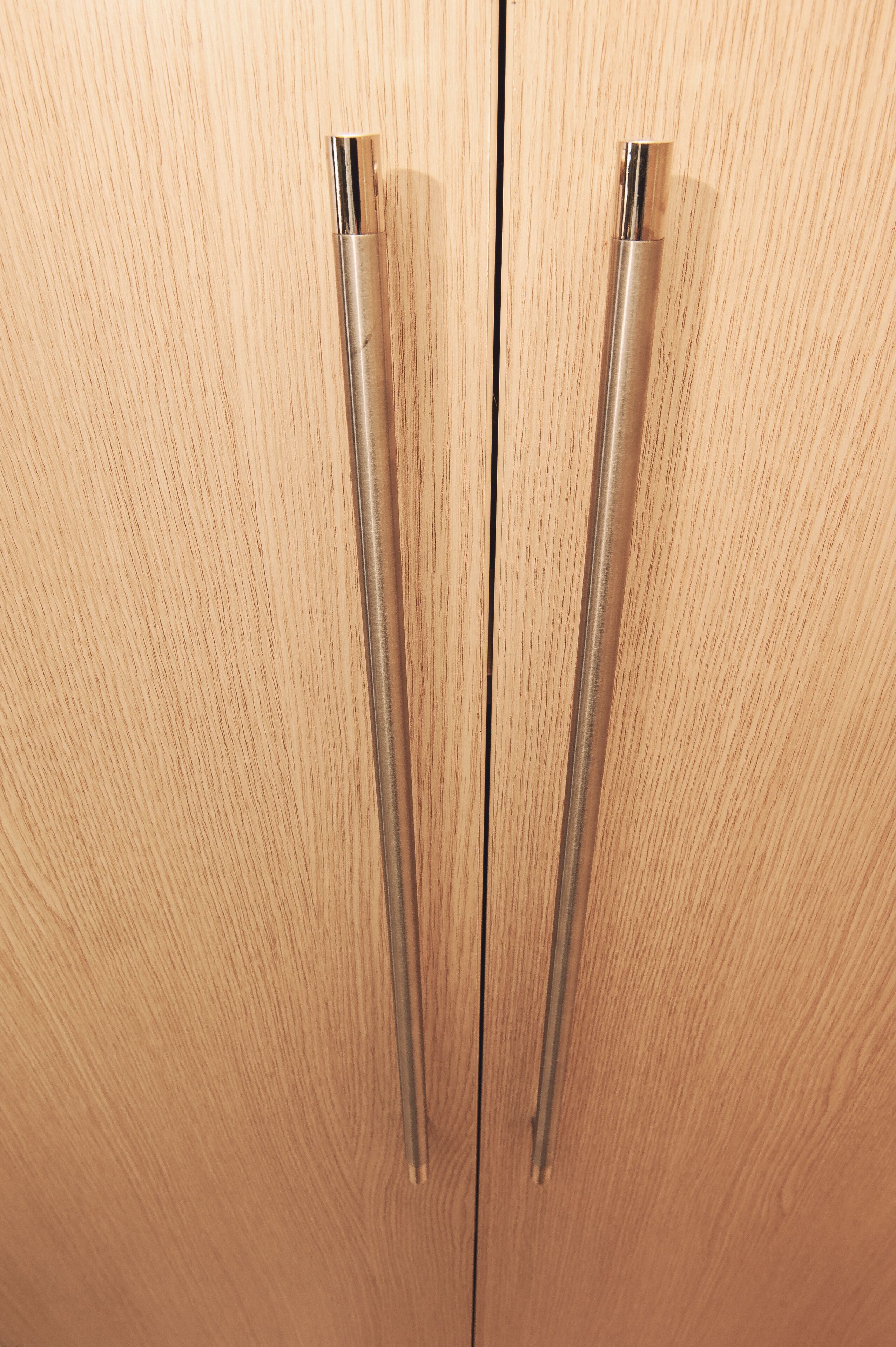 Une porte en bois avec deux poignées métalliques.