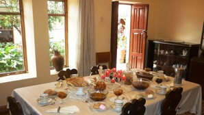 Una mesa de comedor preparada con varios platos, velas y una cafetera.