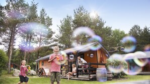 A cabin with a porch, a wooden deck, and a barrel. - Legoland Holiday Village (Billund)