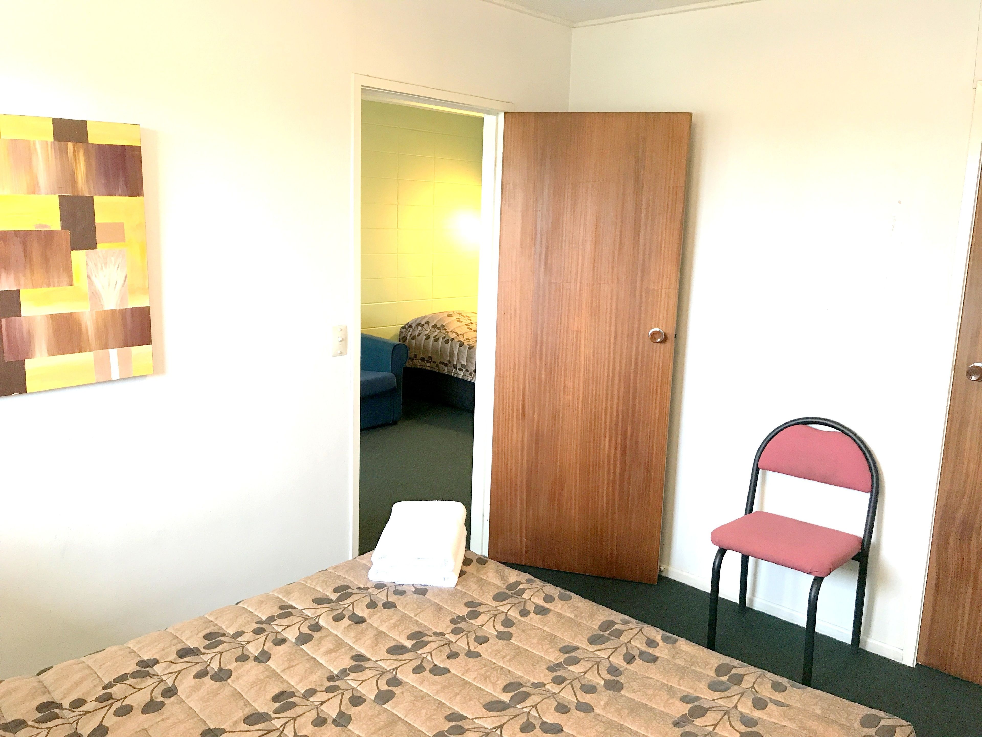 Une pièce avec un lit, une chaise et une porte en bois.