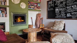 A cozy room with a fireplace, wooden furniture, and a wall with travel-related information. - WIKI HOSTEL Colive - Adults Only & Pet Friendly (Zagarolo)