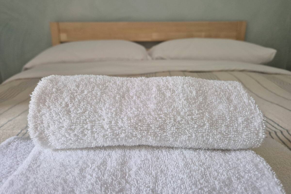 A neatly made bed with two white towels placed on top.