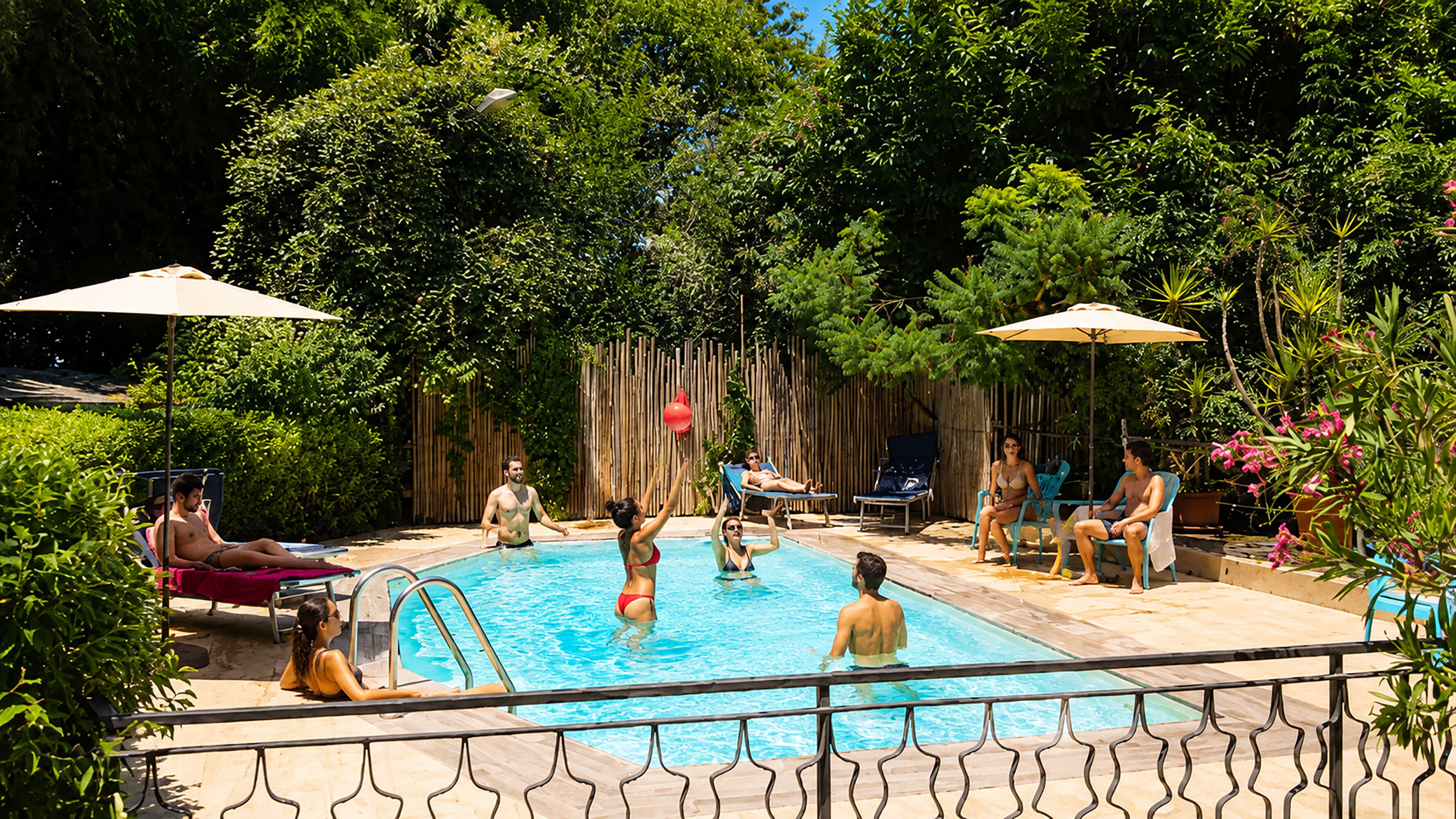 Ein Schwimmbeckenbereich mit Holzterrasse, Liegestühlen und Sonnenschirmen.