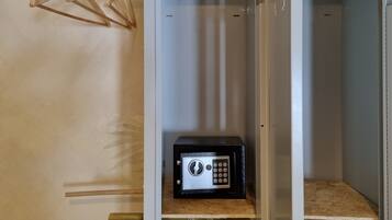 A walk-in closet with a wooden hanger rack, a black safe, and a mirror.