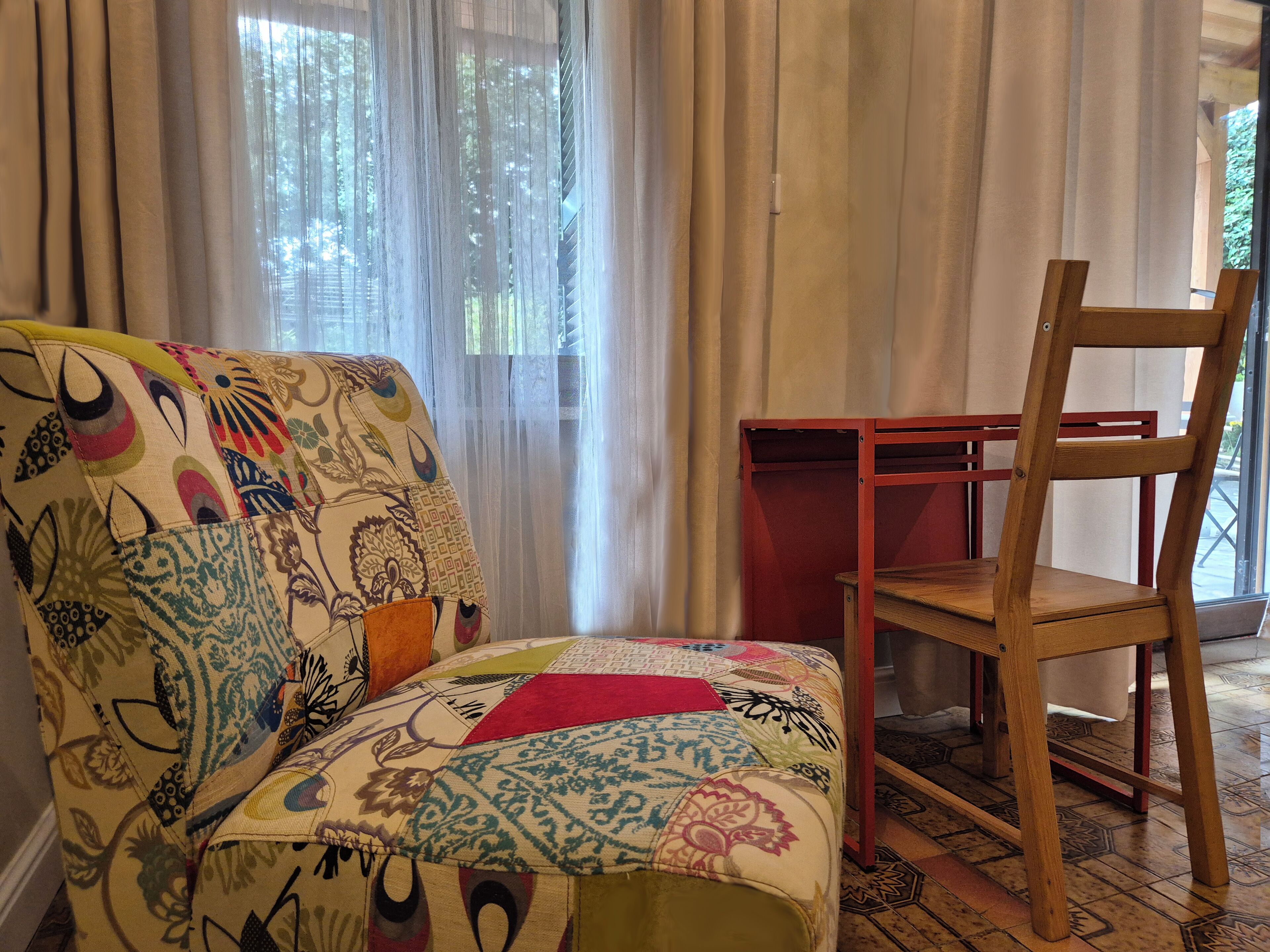 Ein Zimmer mit einer gemusterten Couch, einem Holzsessel und einem kleinen Tisch.