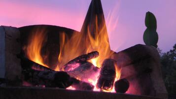 Ein Lagerfeuer mit Holzscheiten und Flammen vor einem Dämmerhimmel.