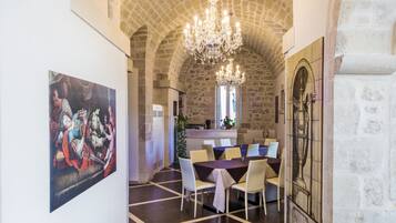 Un espace repas doté d’un plafond en pierre, d’un lustre et d’un tableau au mur.