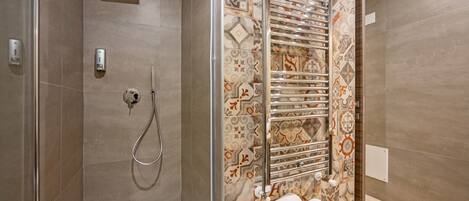 Un baño moderno con ducha, inodoro con cerramiento de vidrio y toallero con toallas dobladas con cuidado.