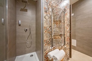 Un baño moderno con ducha, inodoro con cerramiento de vidrio y toallero con toallas dobladas con cuidado.