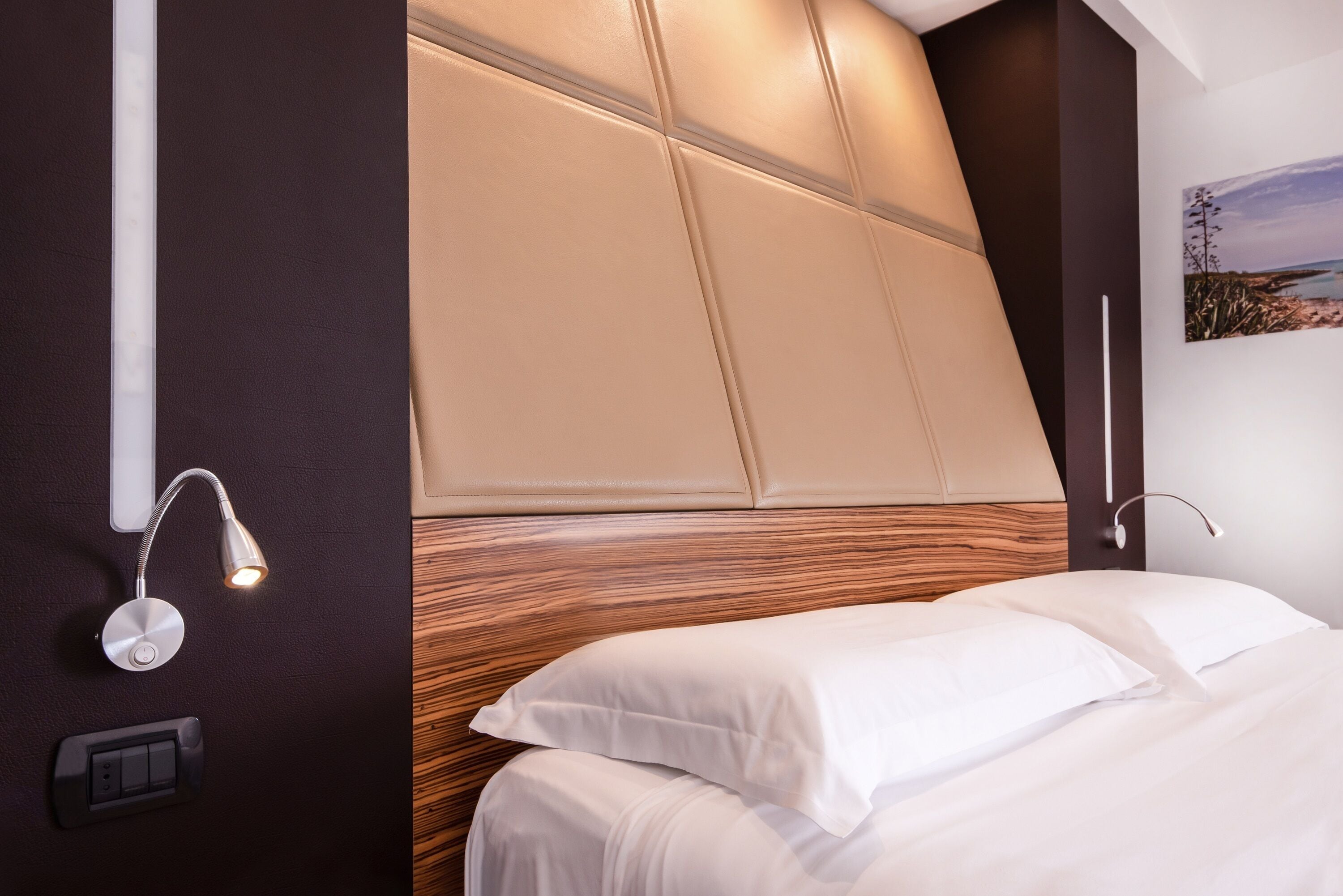 Een moderne hotelkamer met een groot bed, een wandlamp en een stopcontact.