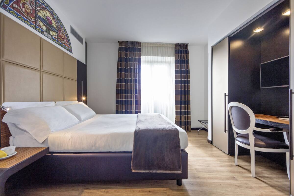 Une chambre d’hôtel moderne avec un grand lit, un bureau et une chaise.