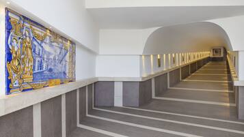 Un couloir d’hôtel moderne, avec un long escalier droit et une mosaïque décorative sur le mur.